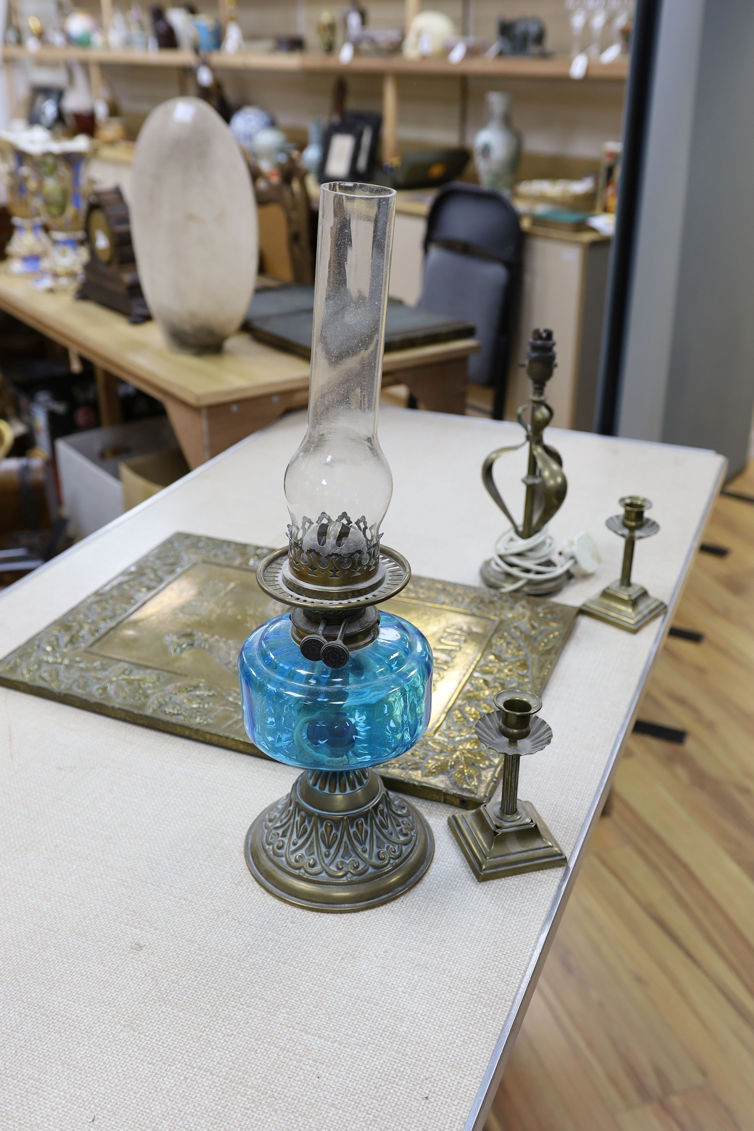 A brass Art Nouveau lamp, a pair of candlesticks, oil lamp and brass Courage advertising sign